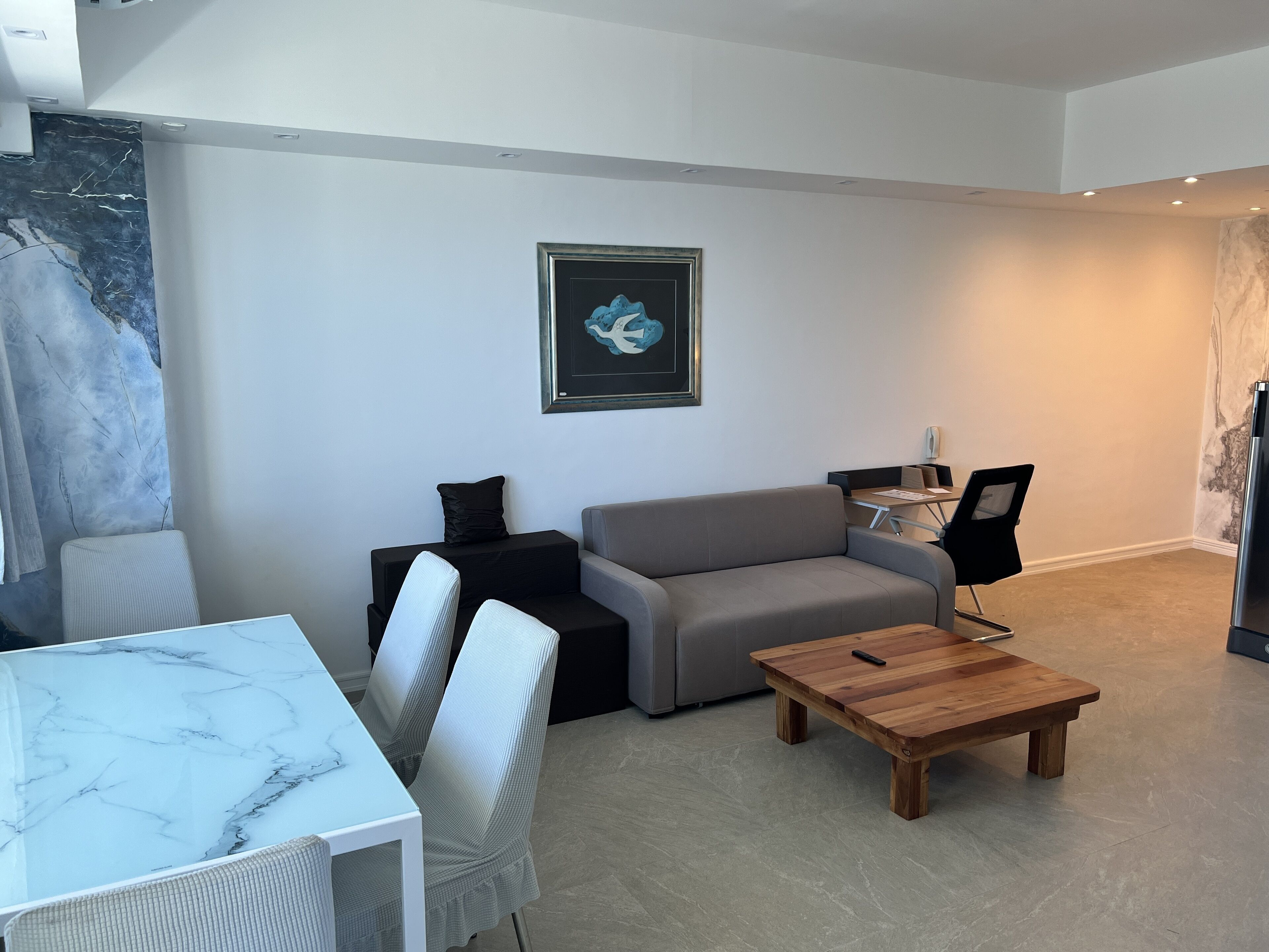 A modern living room with a marble table, grey sofa, and a wooden coffee table.