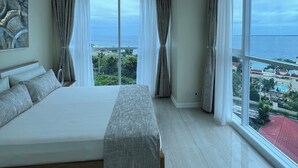 Une chambre spacieuse avec un grand lit, une vue sur la mer et un tableau accroché au mur.