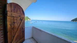 Ein Balkon mit Meerblick, eine Holztür und ein Fliesenboden.