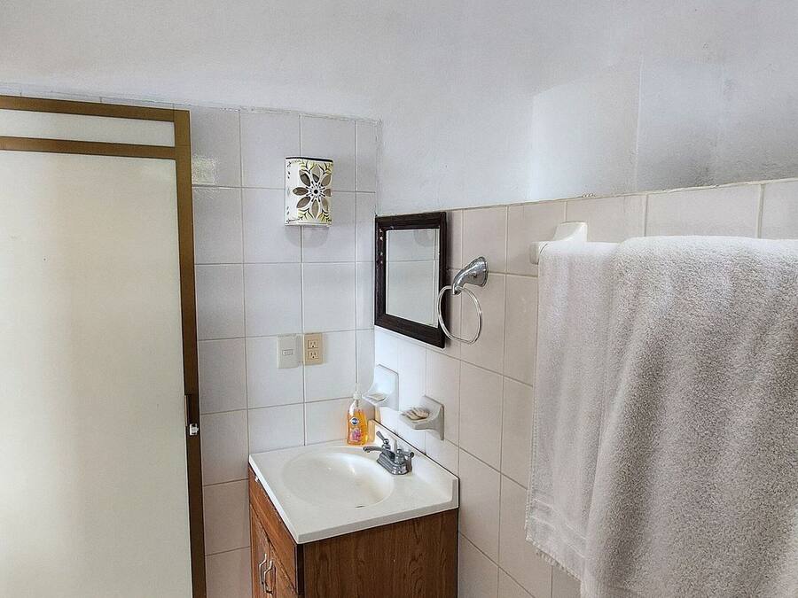 Un baño con tocador de madera, un espejo, toallero y zona de ducha.