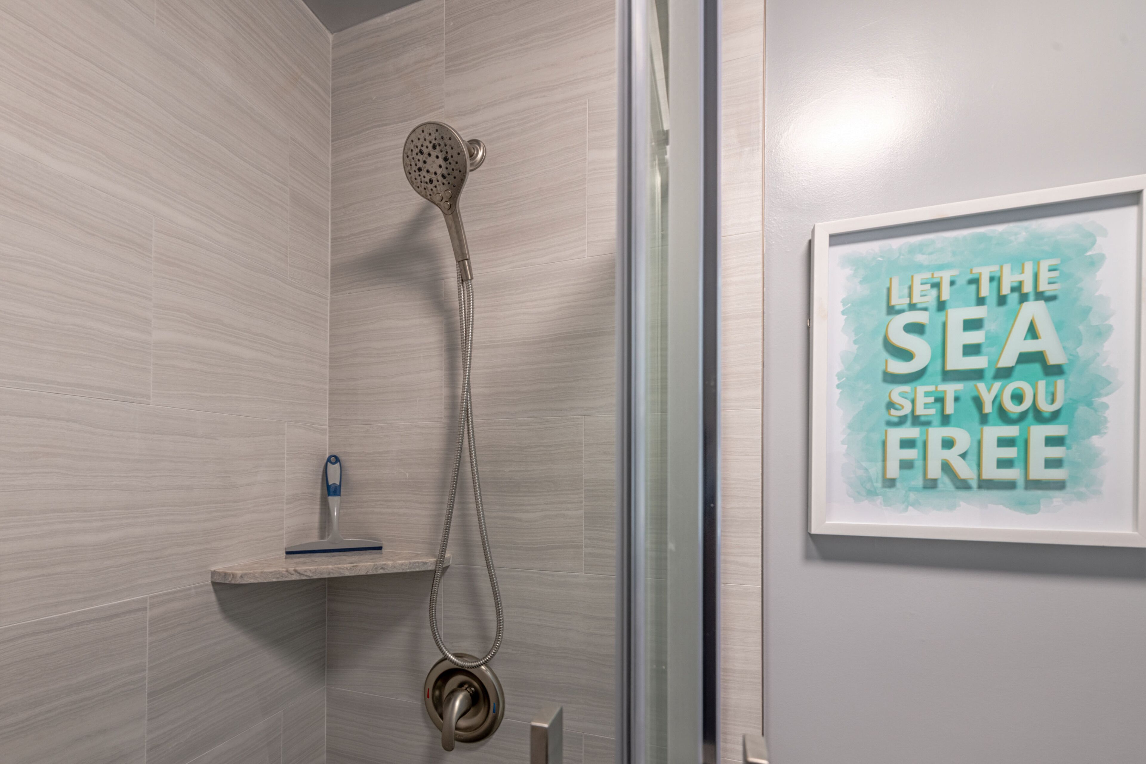 Ein Badezimmer mit Dusche, Handtuchhalter und einem gerahmten Motivationsspruch an der Wand.