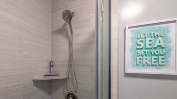 Ein Badezimmer mit Dusche, Handtuchhalter und einem gerahmten Motivationsspruch an der Wand.