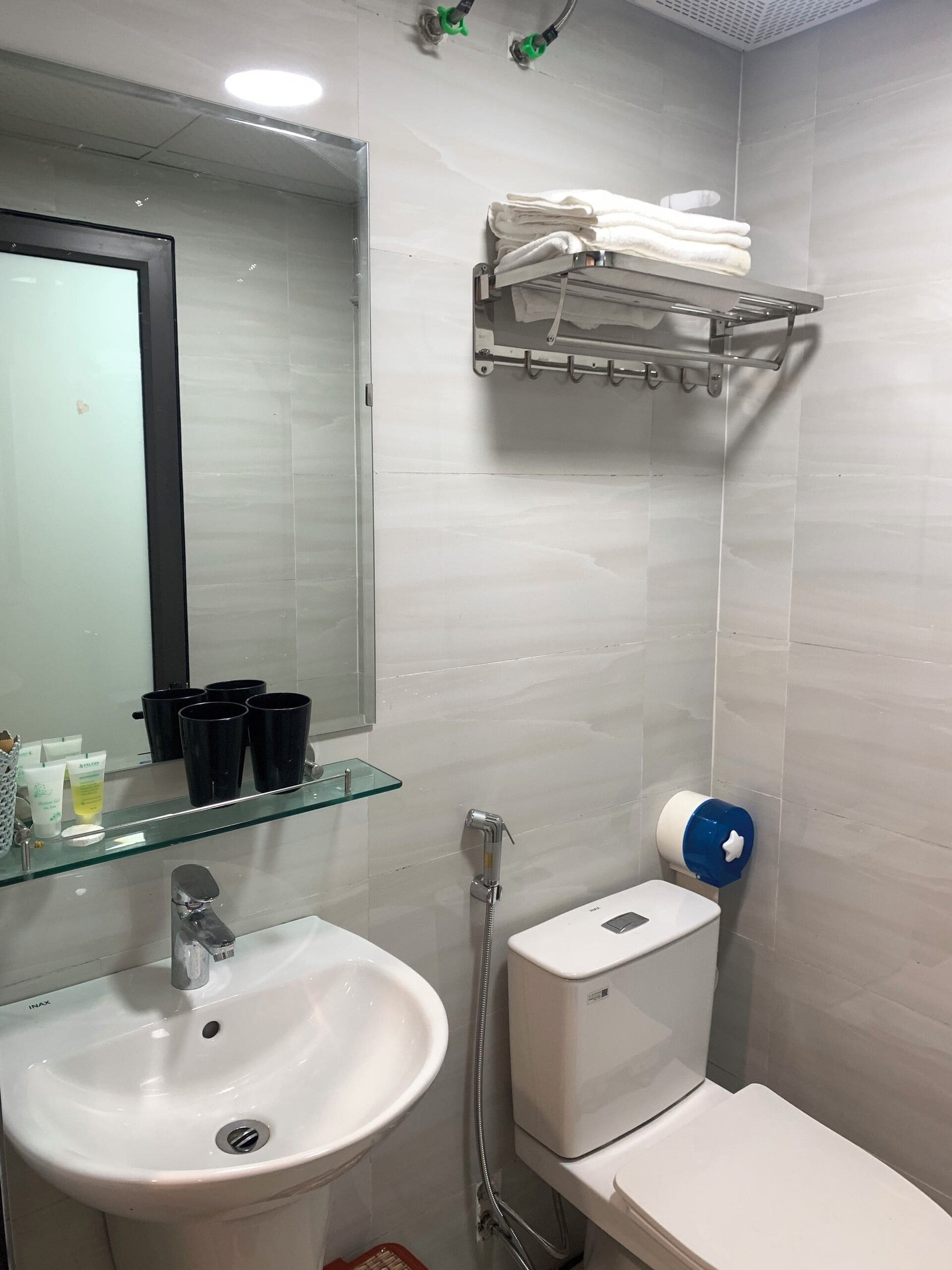 Un baño con lavamanos, inodoro y un perchero para toallas.