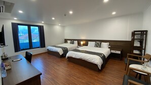 Habitación de hotel con dos camas, un escritorio, una silla, un armario y un ventanal con cortinas.