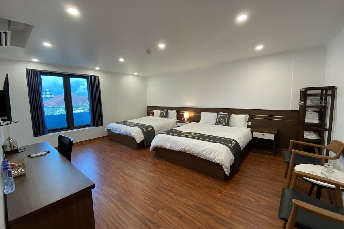 A hotel room with two beds, a desk, a chair, a wardrobe, and a window with curtains.