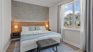 Une chambre d’hôtel moderne avec un grand lit, une table de chevet, un banc et une vue sur l’extérieur.