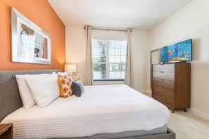 A bedroom with a bed, a dresser, a television, and a window with curtains. - Spacious, Comfortable, Perfect Vacation (Clermont)