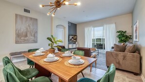 A dining area with a wooden table set for four, surrounded by green upholstered chairs. - Spacious Condo-Modern Decor, Star Wars Bedroom (Four Corners)