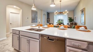 A modern kitchen with a central island, built-in appliances, and pendant lighting. - Spacious Condo-Modern Decor, Star Wars Bedroom (Four Corners)
