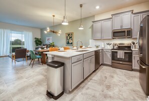 Enjoy cooking in this well-equipped kitchen with a central island, stainless steel appliances, and a dining area.