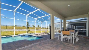 Ein überdachter Außenbereich mit Pool, Gartenmöbeln und Grill.