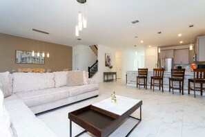 A modern living room with a sofa, coffee table, and dining area with chairs.