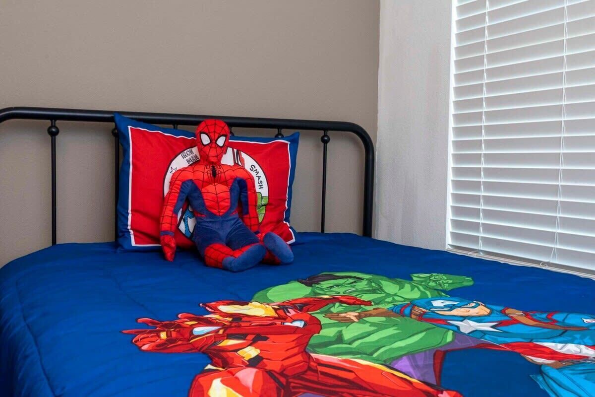 Ein Bett mit einem Spider-Man Kopfkissen und einer Bettdecke im Superhelden-Design.