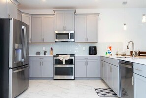 Enjoy cooking in this well-equipped kitchen with a stainless steel refrigerator, microwave, and oven.