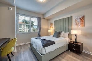 Een moderne hotelkamer met een bed, nachtkastje, lamp en uitzicht.