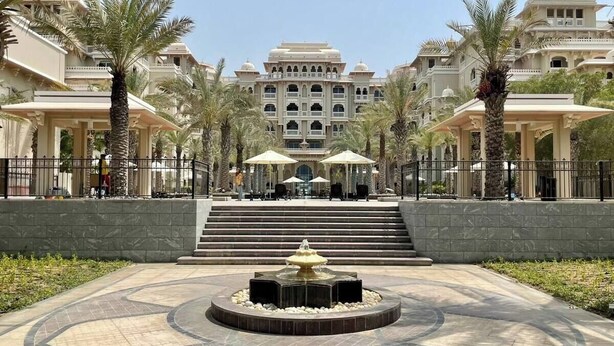 A grand hotel with a central fountain, palm trees, and a large staircase leading to the entrance. - NEW Direct Golf View Sport City 2BD (Dubai)