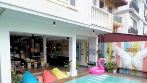 A pool area with a pink flamingo decoration and a sign with white wings. - LOTUS SERENITY Hostel (Siem Reap)