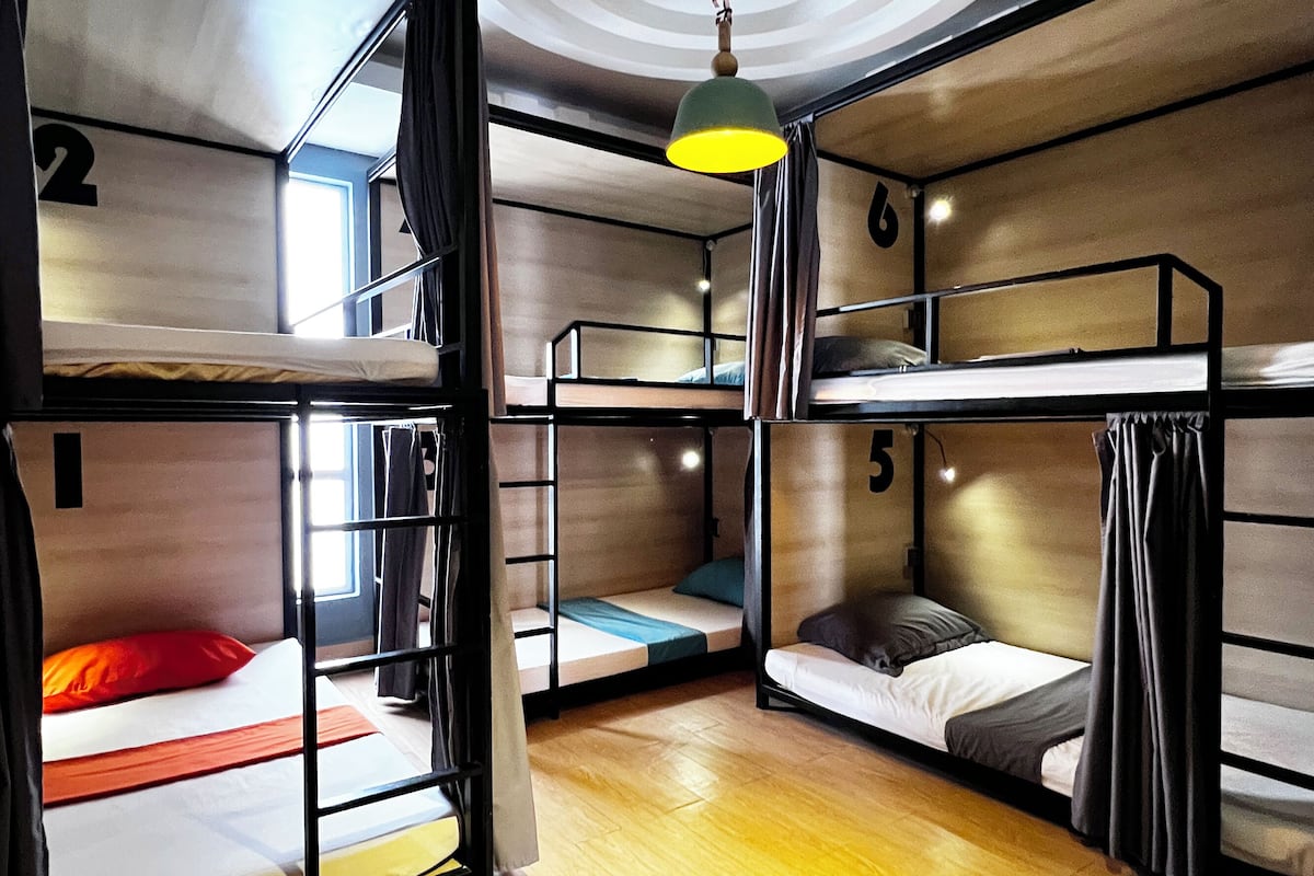 Ein Schlafsaalzimmer mit Etagenbetten, Holzboden und einem runden Deckenmuster.