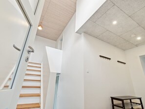 A modern interior with a staircase, a small table, and a ceiling light.