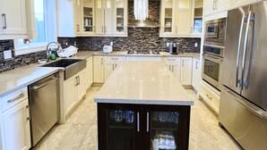 A modern kitchen with a central island, stainless steel appliances, and a decorative chandelier. - Jennifers House (Vancouver)