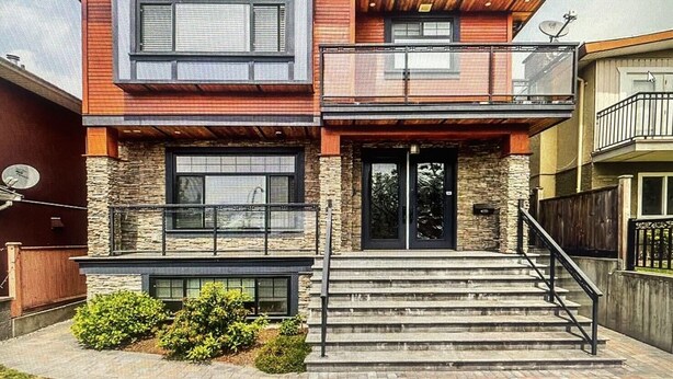 A modern two-story house with a stone facade, large windows, and a balcony. - Jennifers House (Vancouver)