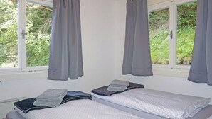 A room with two beds, grey curtains, and a view of greenery outside. - Lieblingsplatz by Interhome (Flirsch)