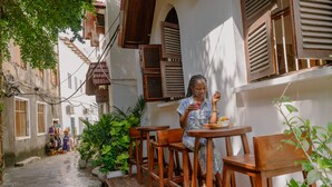 A narrow street with wooden furniture and potted plants. - Shoki Shoki Hotel Stone Town (Zanzibar Town)