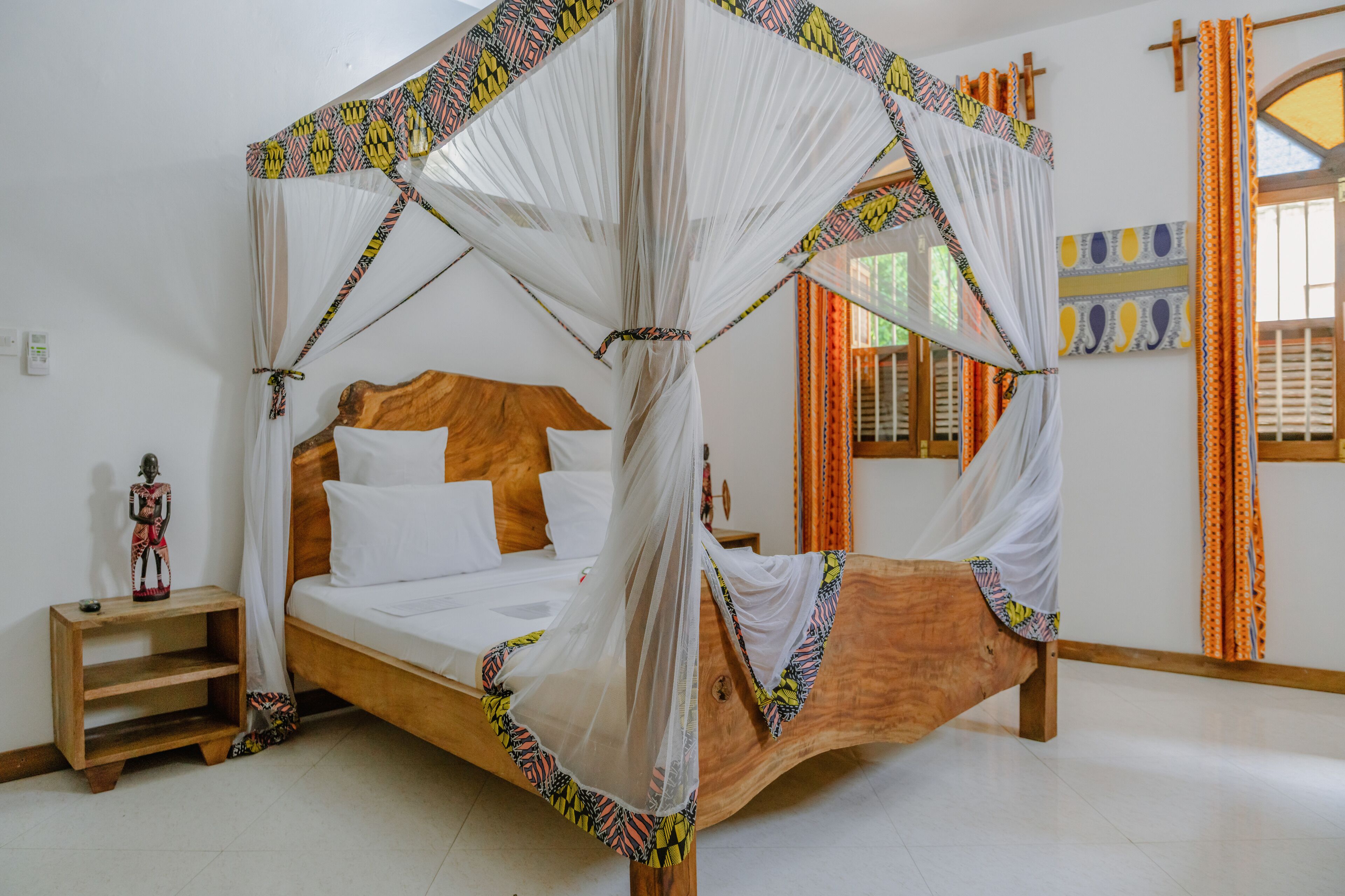 A bed with a canopy, a wooden headboard, and a nightstand with a small statue.