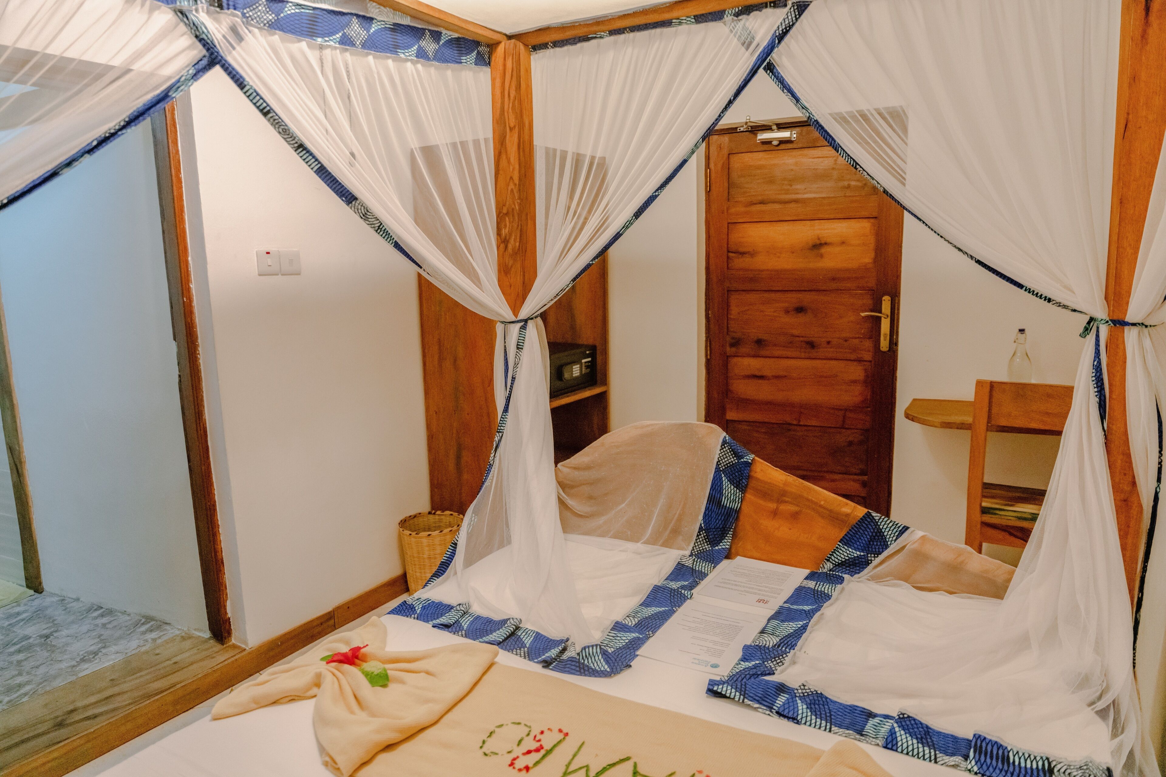 Une chambre à coucher avec un lit surmonté d’un dais, des meubles en bois et une petite table de chevet.