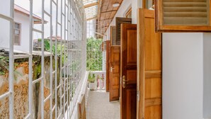 A narrow corridor with a wooden door, a white wall, and a metal gate. - Shoki Shoki Hotel Stone Town (Zanzibar Town)