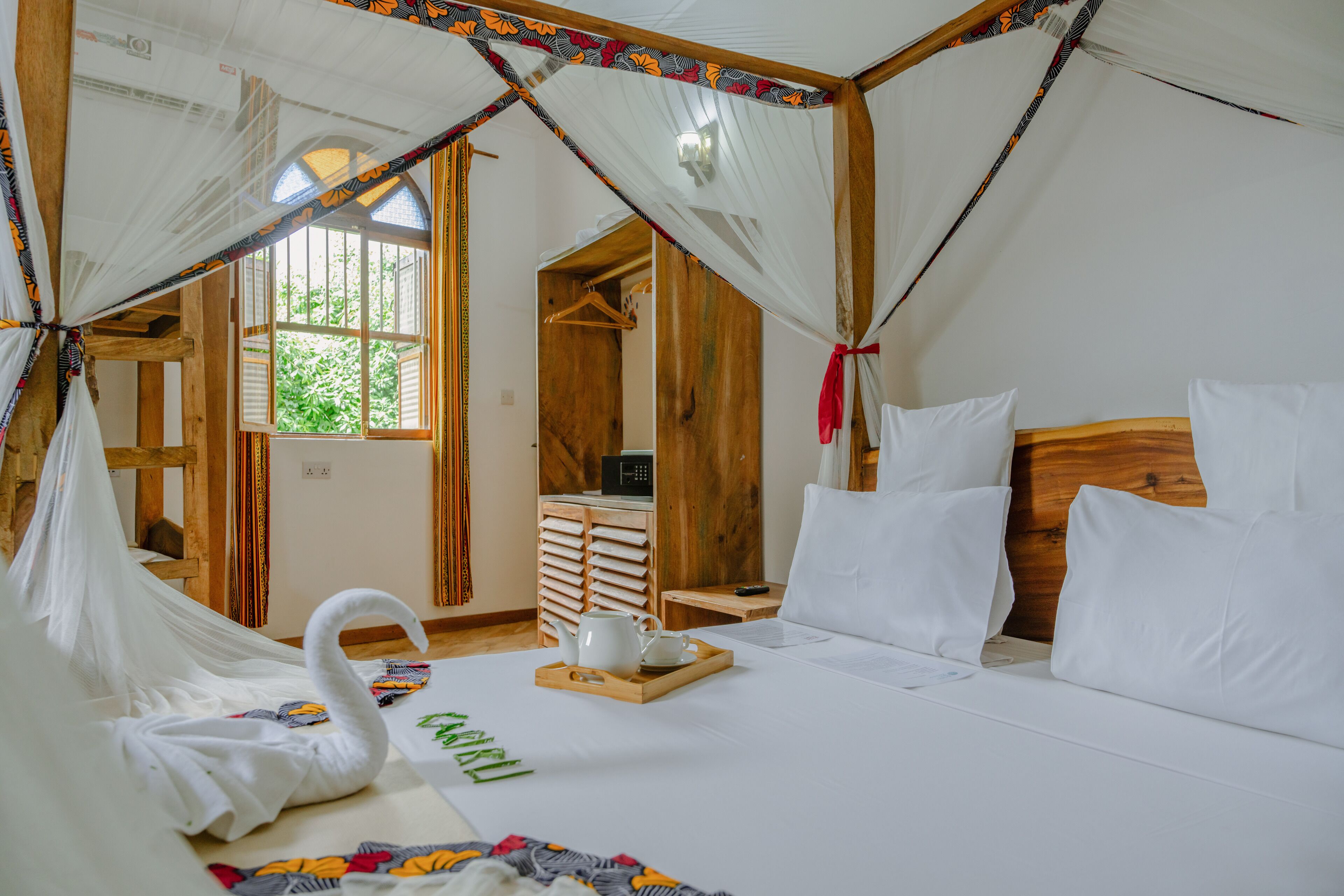A room with a bed, a wooden headboard, a bedside table with a tray, and a window with curtains.