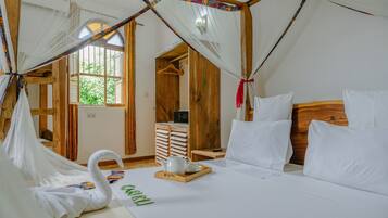 A room with a bed, a wooden headboard, a bedside table with a tray, and a window with curtains.