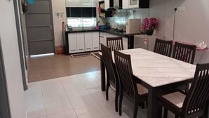 Una cocina compacta con armarios blancos, una mesa de comedor con sillas y una ventana con persianas.