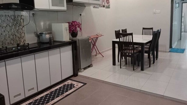 Una cocina moderna con armarios blancos, encimera negra y un comedor con mesa y sillas.