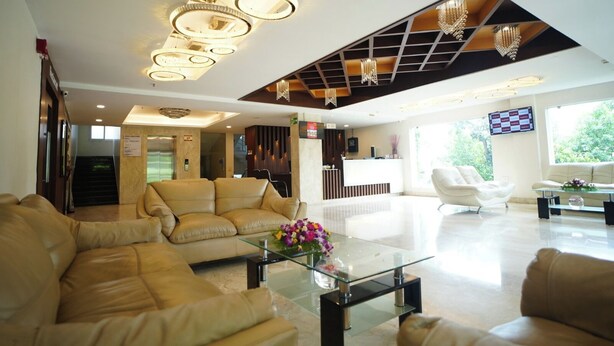 A spacious lobby with leather sofas, a glass coffee table, and a reception desk.