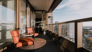Un balcón con una silla de cuero, una mesita y una planta en maceta.
