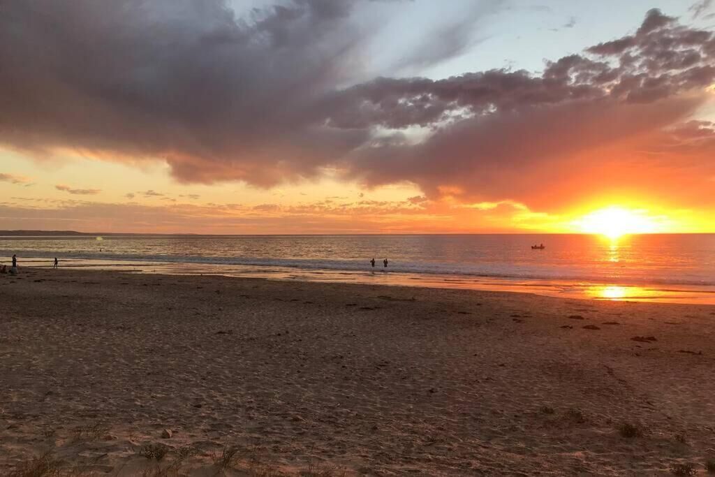 Une plage au coucher du soleil, avec un ciel dégagé et une mer calme.