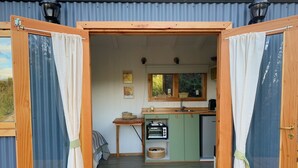Een kleine keuken met een spoelbak, een tafeltje en een raam.