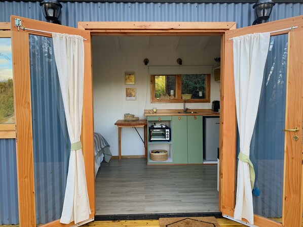 Una cocina pequeña con un lavamanos, una mesita y una ventana.
