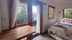 Een kamer met een houten bank, een bed met een deken en een raam met gordijnen.