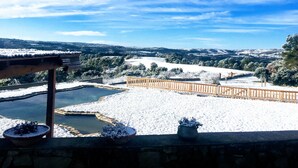 Paisaje nevado con una terraza de madera y un muro de piedra.