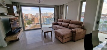 A modern living room with a sofa, a coffee table, and a TV on a stand.