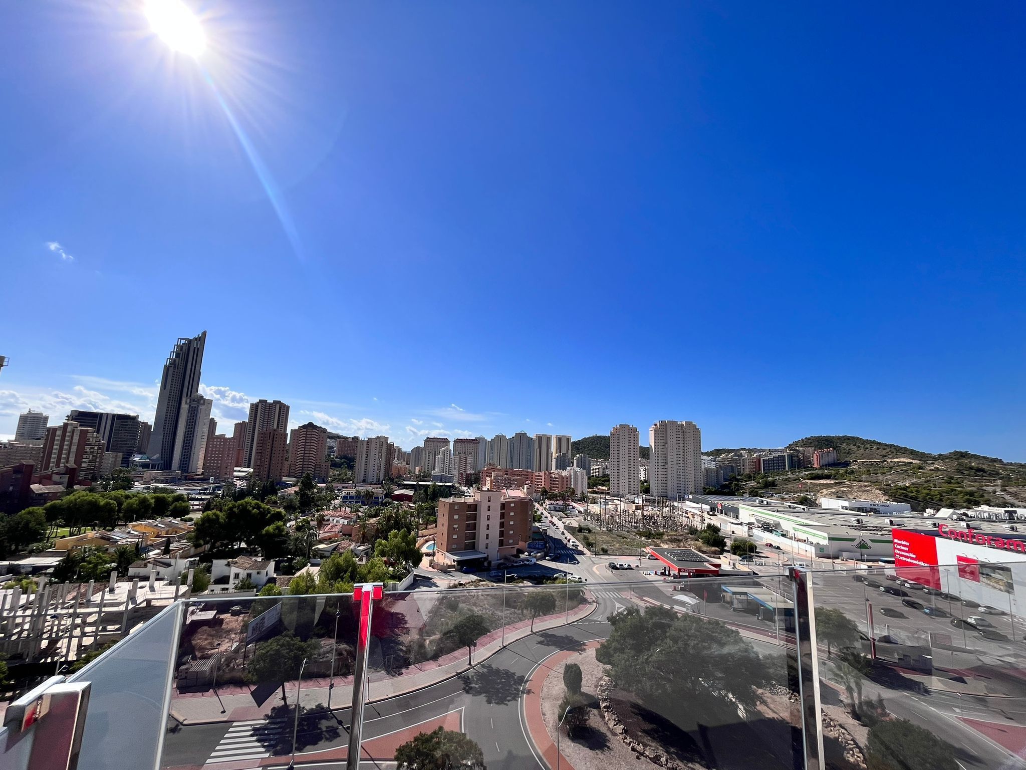 A cityscape with high-rise buildings, a roundabout, and a clear blue sky.