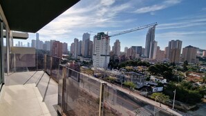 A balcony with a city view, including high-rise buildings and a construction crane.