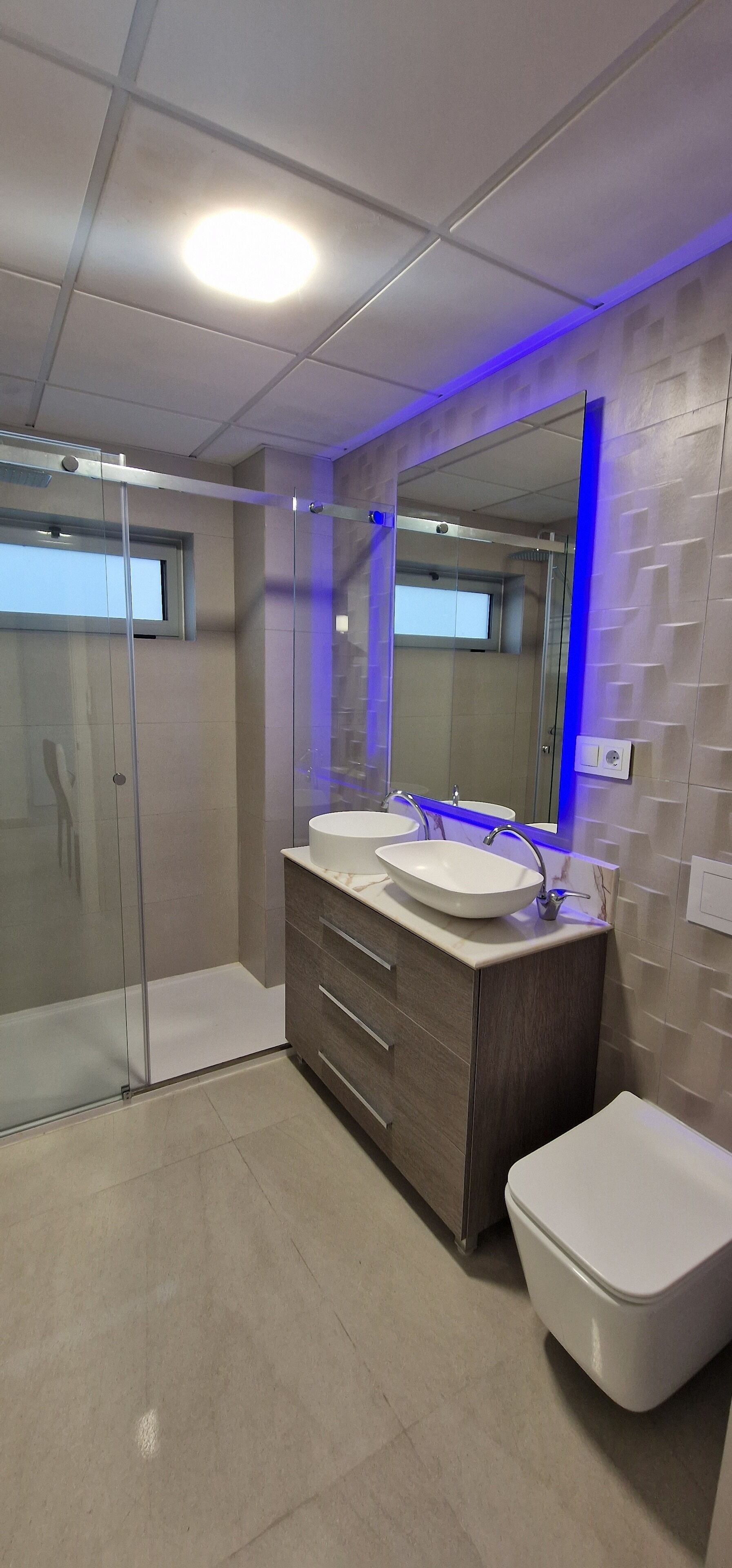 Une salle de bain moderne avec deux lavabos, une douche et des toilettes.