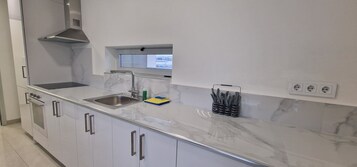 Una cocina moderna con un lavaplatos de acero inoxidable, una ventana sobre el lavaplatos y un horno empotrado.