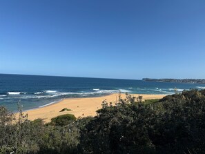 A beach with clear blue sky and ocean waves. - Cozy House in Forresters Beach - modern interiors (Forresters Beach)