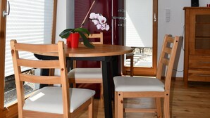 A dining area with wooden chairs and a table, a red refrigerator, and a potted orchid. - New 2 room apartment in Murnauer Moos (Schwaigen)