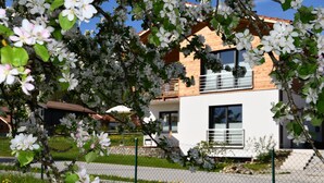 A modern two-story building with a white facade and wooden accents. - New 2 room apartment in Murnauer Moos (Schwaigen)