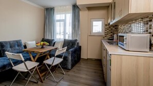 A compact living space with a sofa, a small dining table, and a kitchenette. - Carvan Hotel (Istanbul)